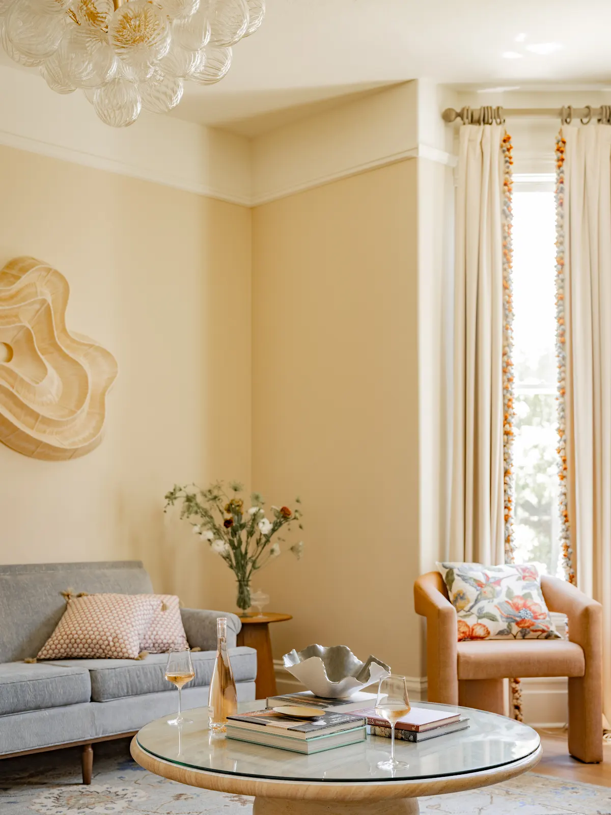 Sunlit sitting room with a gray sofa, peach armchair, and round coffee table.