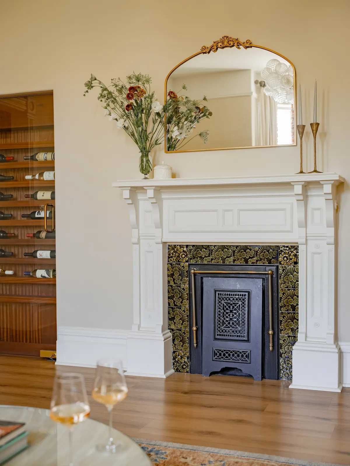 Decorative fireplace with a white mantel, gold mirror, and flowers.