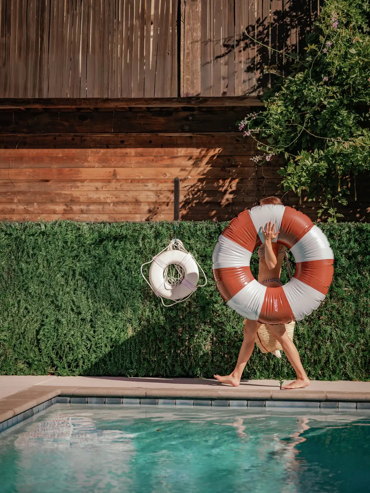 Guest holding a striped life ring beside the swimming pool.