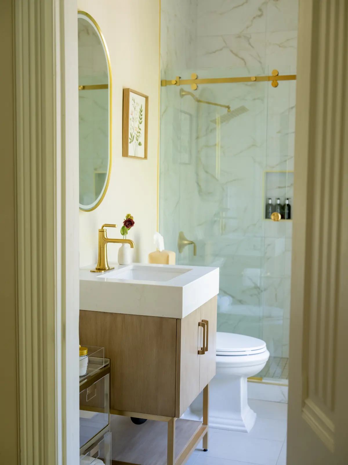 Bathroom vanity and marble-patterned shower viewed through an open doorway.