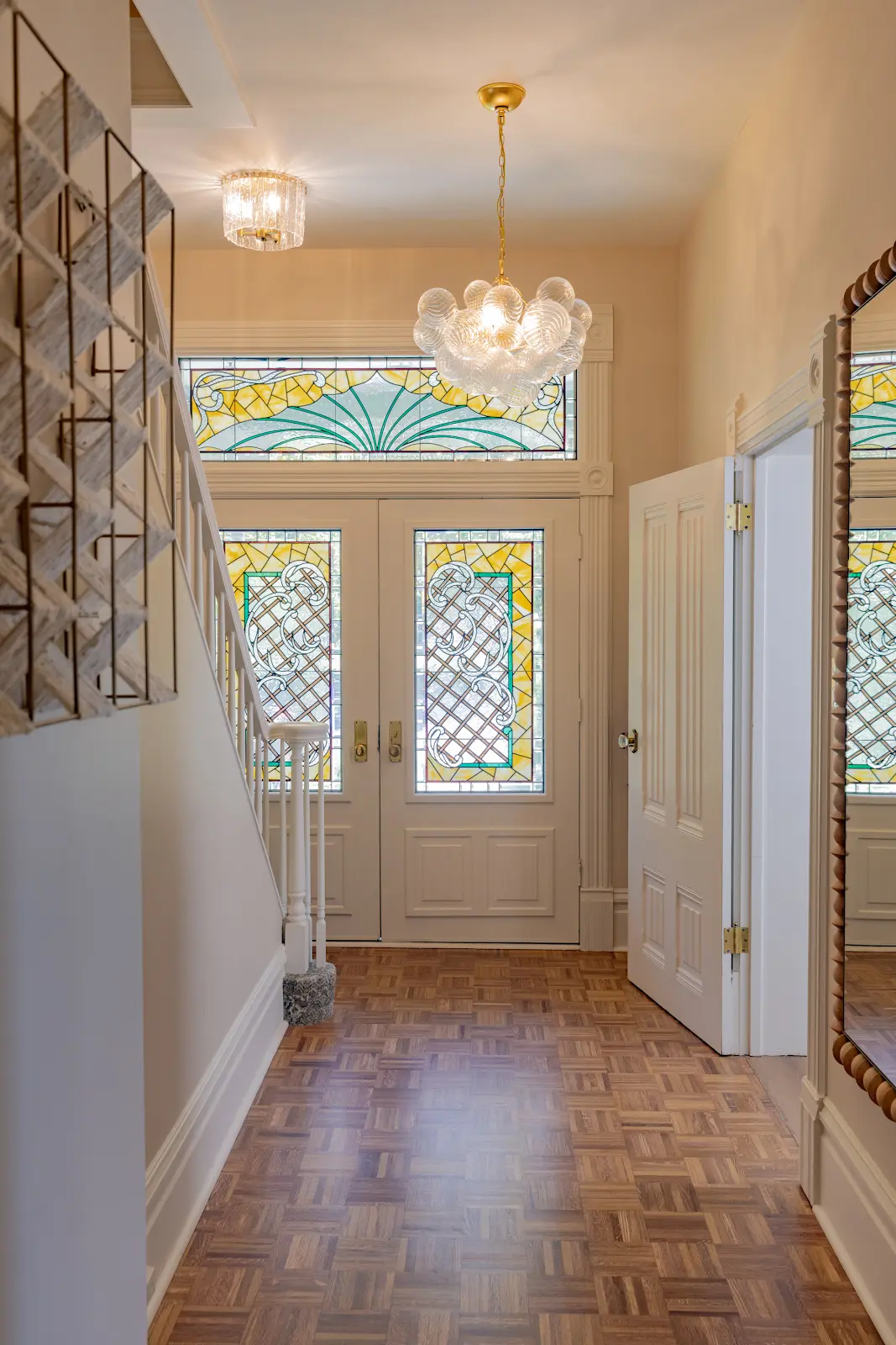 Entry hallway with parquet flooring, a glass chandelier, and stained glass doors.