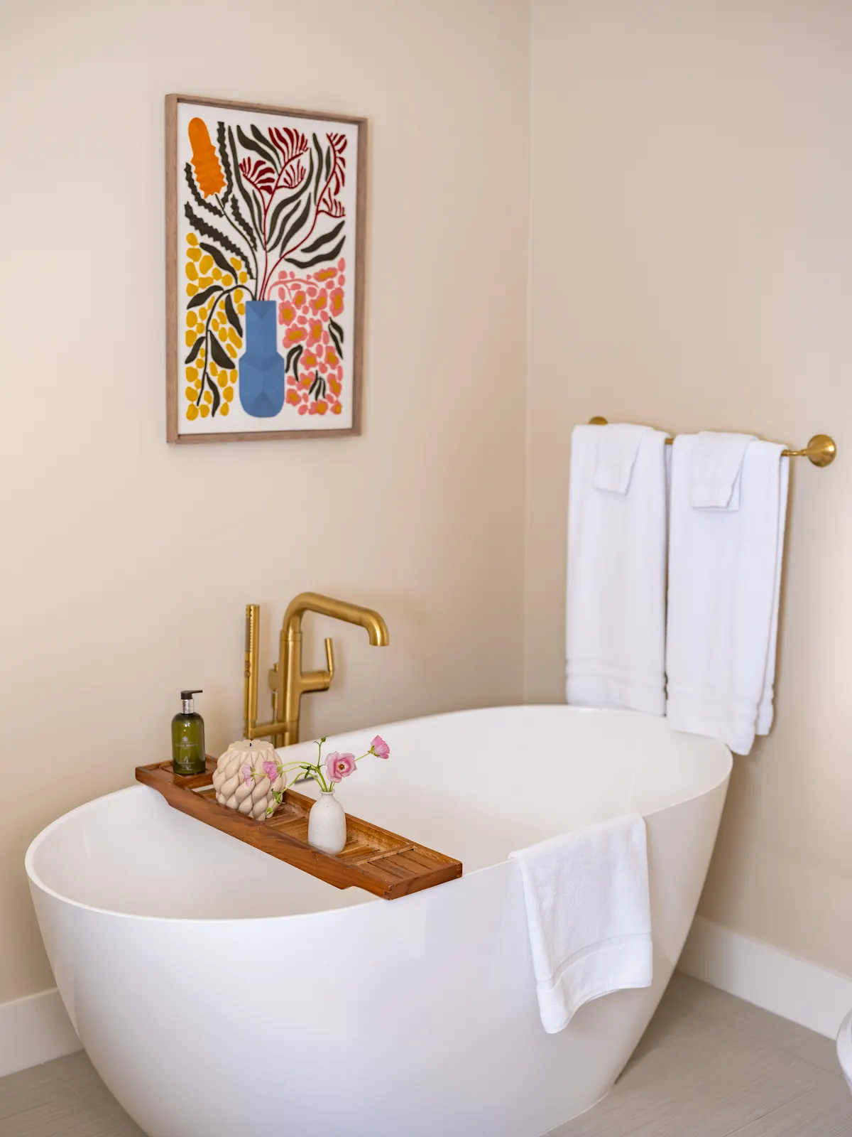 Freestanding bathtub with a wooden bath tray and brass faucet.