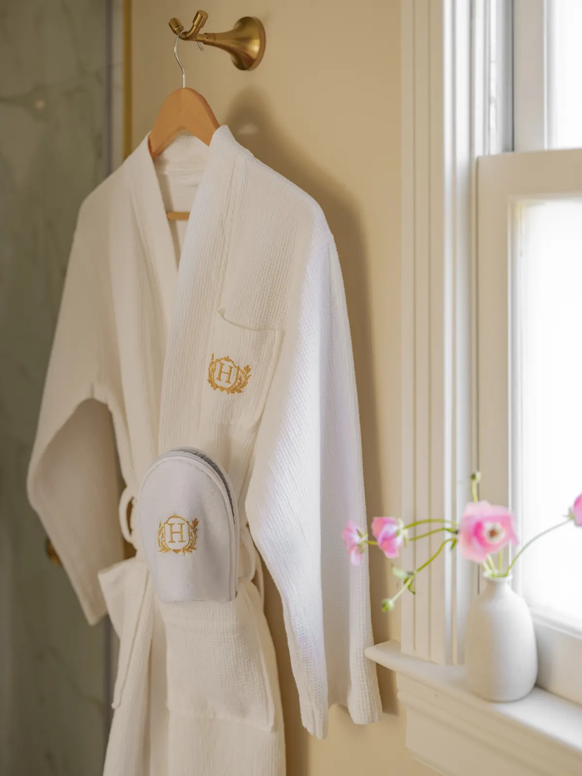 White embroidered bathrobe hanging beside a bright window.