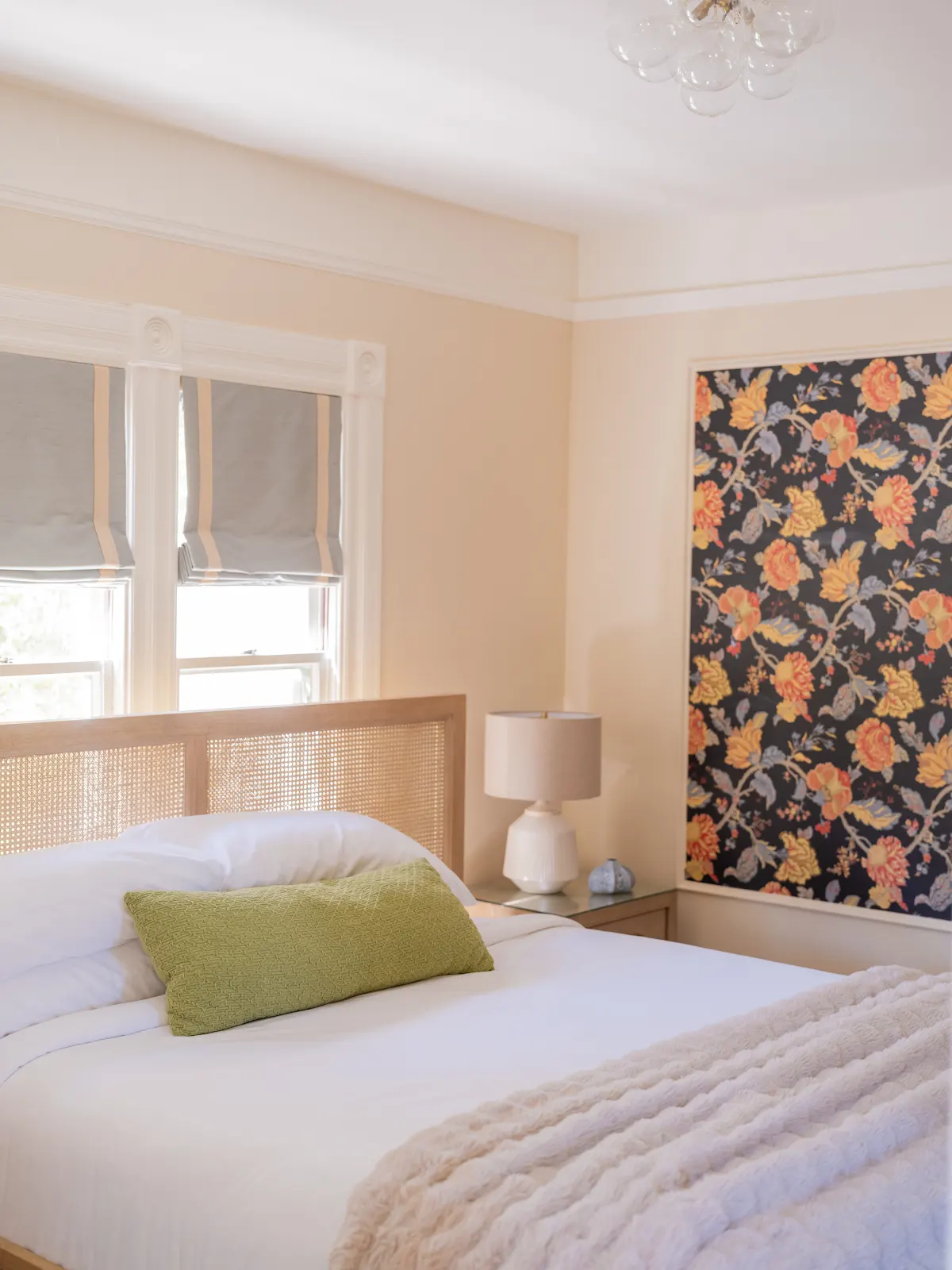 Guest room with white bedding, a green accent pillow, and floral wallpaper.
